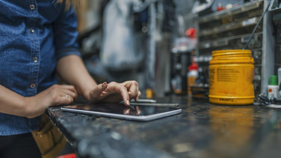 Eine Handwerkerin arbeit in der Werkstatt mit ihrem Tablet