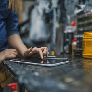 Eine Handwerkerin arbeit in der Werkstatt mit ihrem Tablet