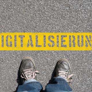 Eine Person blickt von oben auf ihre Füße und einen Schriftzug „Digitalisierung“